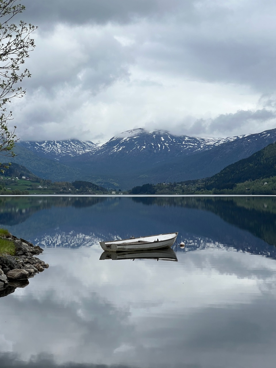 A white rowboat resting on a mirror-still Norwegian lake